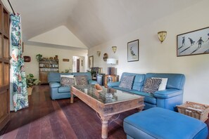 A living room with a blue sofa, a glass coffee table, and a wooden cabinet.