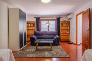 A living room with a sofa, a coffee table, a lamp, a bookshelf, and a door.