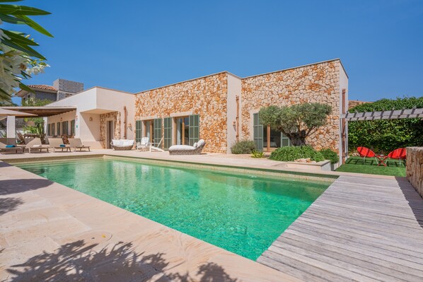 A modern house with a swimming pool, outdoor seating, and a stone facade.