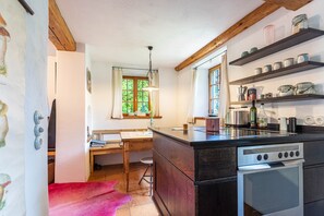 A kitchen with wooden cabinets, a built-in oven, and a window with curtains.