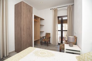 A bedroom with a bed, a wardrobe, a chair, a nightstand, and a window with curtains.