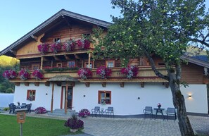 Un chalet en bois doté d’un balcon, d’un espace salon extérieur et d’un pommier.