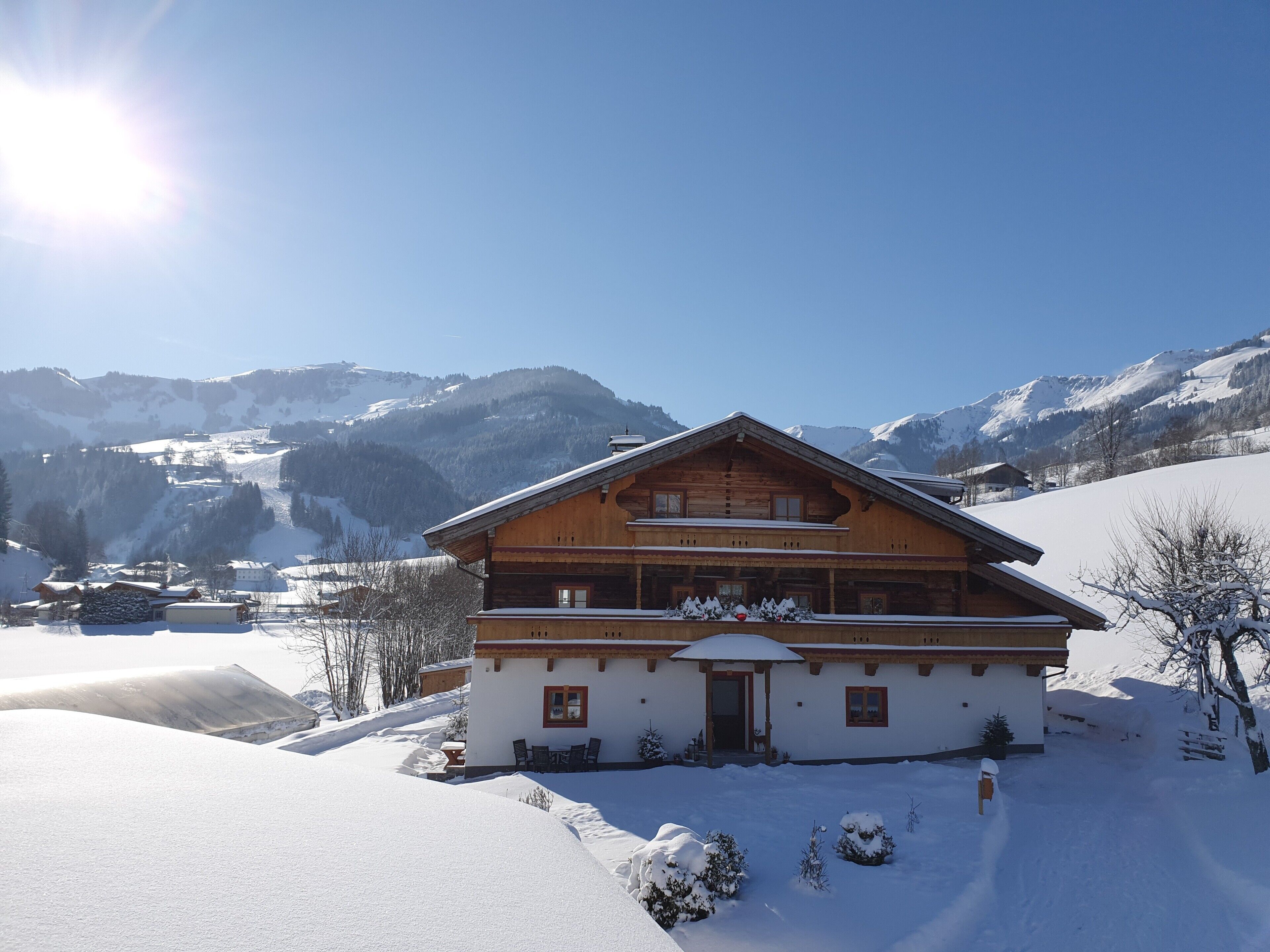 Een houten chalet met een balkon, omgeven door sneeuwbedekte heuvels en bergen.
