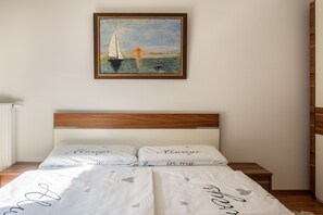A bedroom with a wooden headboard, two bedside tables, and a painting of a sailboat on the wall.