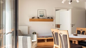 Un salon moderne comprenant un canapé, une table à manger avec des chaises, une cheminée et un luminaire au plafond.