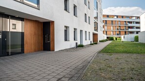 Un bâtiment moderne doté d’un chemin piétonnier pavé, de grandes fenêtres et d’une zone herbeuse.