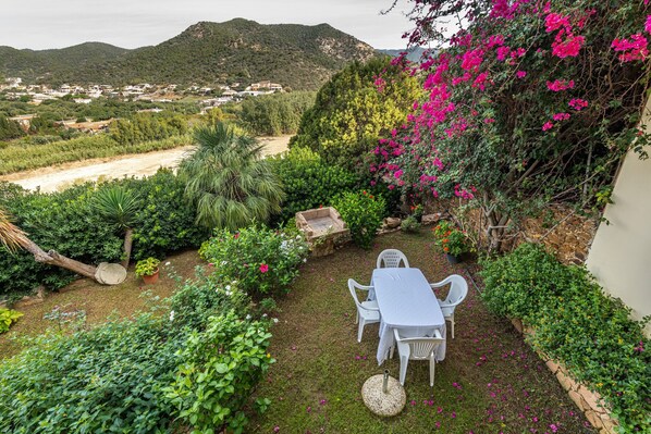 Un jardin avec une table et des chaises, entouré de verdure et de fleurs.