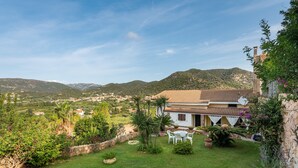 A house with a garden, white chairs, and a view of the countryside. - Beautiful Villa "Chia" Close to Beach with Sea View & Garden (Domus de Maria)