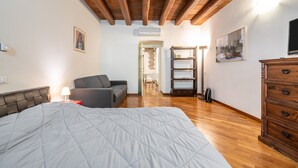 Un dormitorio con una cama, un sofá, un aparador, un televisor y una estantería.