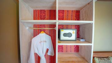 A wooden wardrobe with a red patterned interior, a white robe hanging on the door, and a radio on the top shelf.