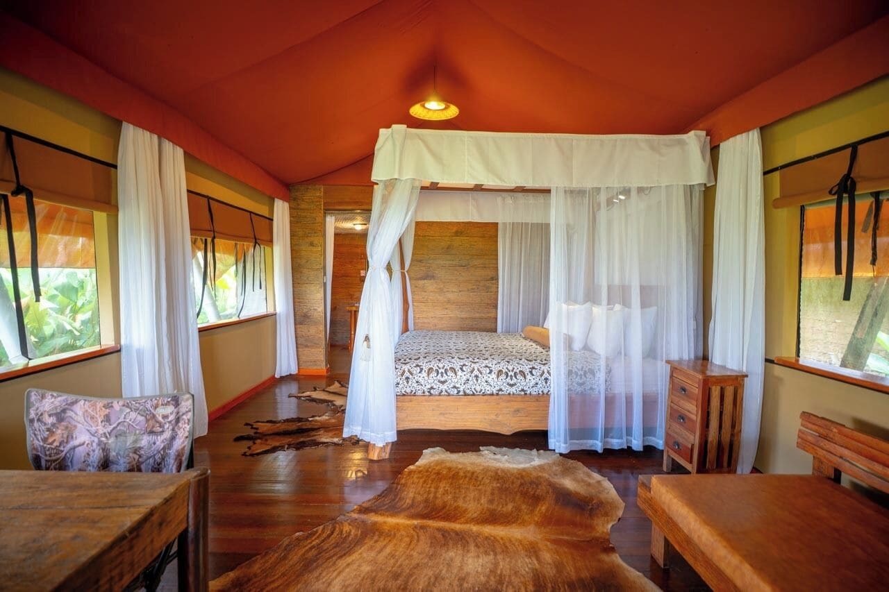 Ein Zimmer mit einem Himmelsbett, Holzmöbeln und einem großen Fellteppich.