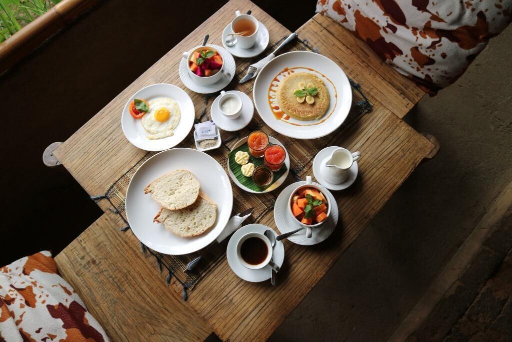 A breakfast table with various dishes including eggs, pancakes, toast, and soup.