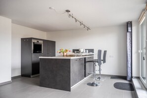 A modern kitchen with a central island, bar stools, and a built-in oven.