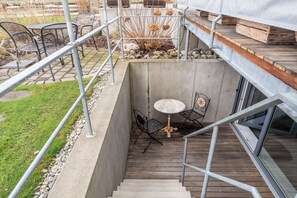 Una escalera de hormigón conduce a una terraza con mobiliario exterior y vistas del paisaje circundante.