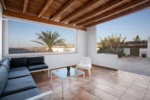Un patio extérieur moderne avec un canapé, une table à plateau en verre et une chaise blanche.