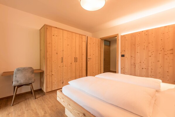 Une chambre à coucher avec une armoire en bois, un bureau et un lit.