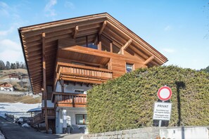 Un chalet de madera con techo inclinado, un letrero privado y un seto en primer plano.
