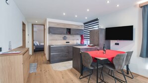 A modern kitchen with a dining area, built-in appliances, and a flat-screen TV. - Modern Apartment "Ulli" Close to Cable Cars with Mountain View & Wi-Fi (St. Christina)