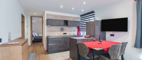 Una cocina moderna con comedor, electrodomésticos integrados y un televisor de pantalla plana.