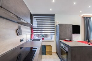 Una cocina moderna con electrodomésticos integrados, una ventana con persianas y un televisor de pantalla plana.