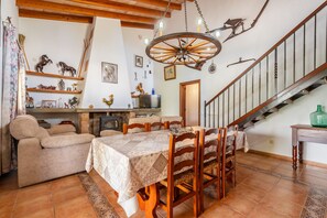 A dining area with a table set for four, a sofa, and a staircase with a wooden railing.