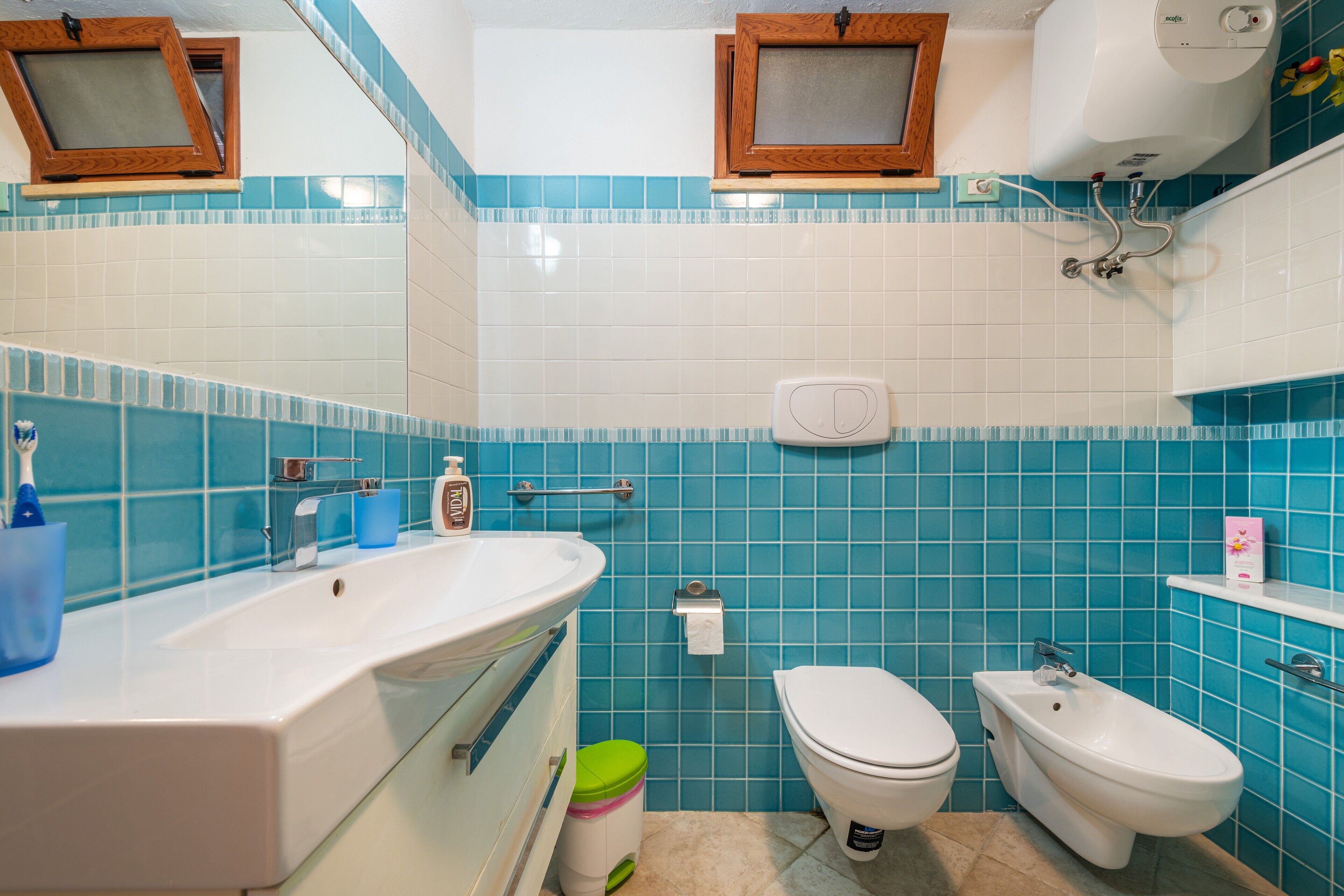 Un bagno con lavandino, water, bidet e piastrelle blu.