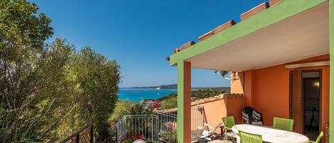 A terrace with a table and chairs, overlooking a coastal landscape.