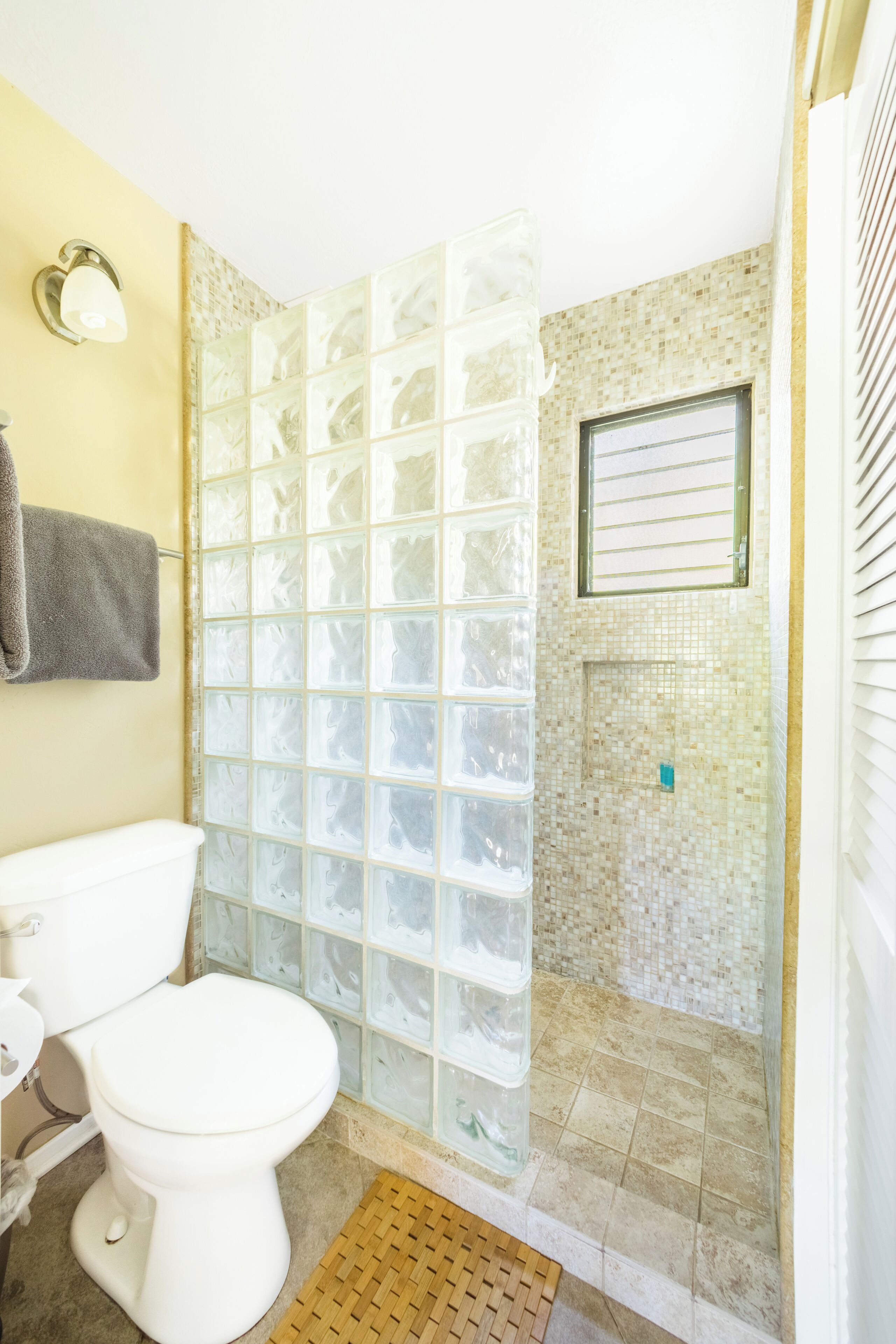 Un baño con cabina de ducha de vidrio, inodoro y pared de ducha azulejada.
