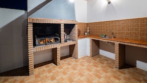 A kitchen with a brick oven, a sink, and a tiled backsplash.