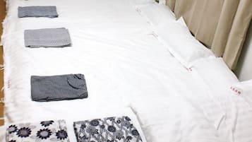 A neatly made bed with white sheets and several decorative pillows.