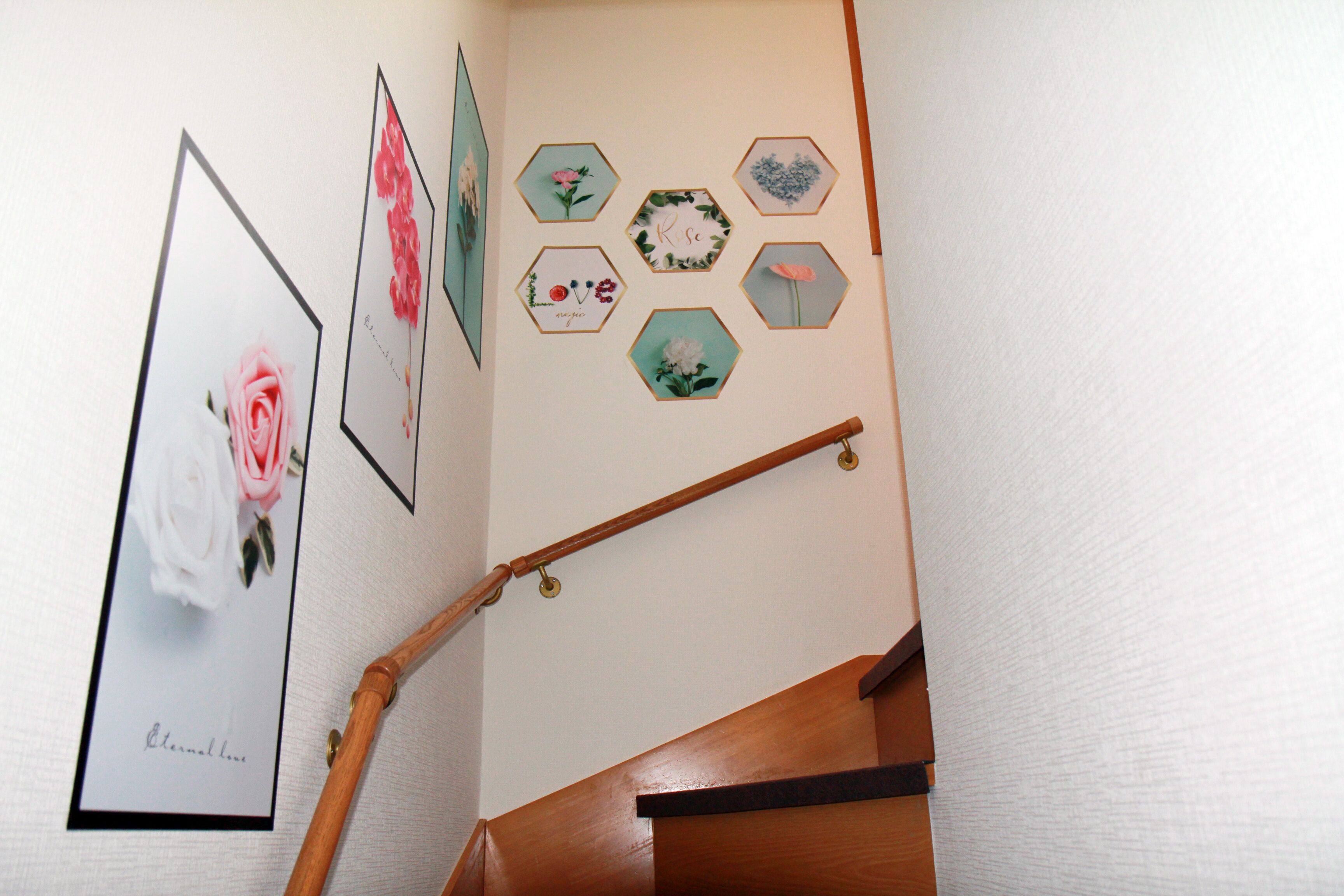 A staircase with a wooden handrail and a wall decorated with hexagonal frames containing floral designs.