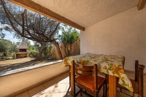 Patio con tavolo e sedie, vista su alberi e zona barbecue.