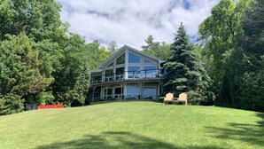 A two-story house with a large front lawn, surrounded by trees. - Luxury Cottage on ice-fishing Rice Lake and year round activities (Bewdley)