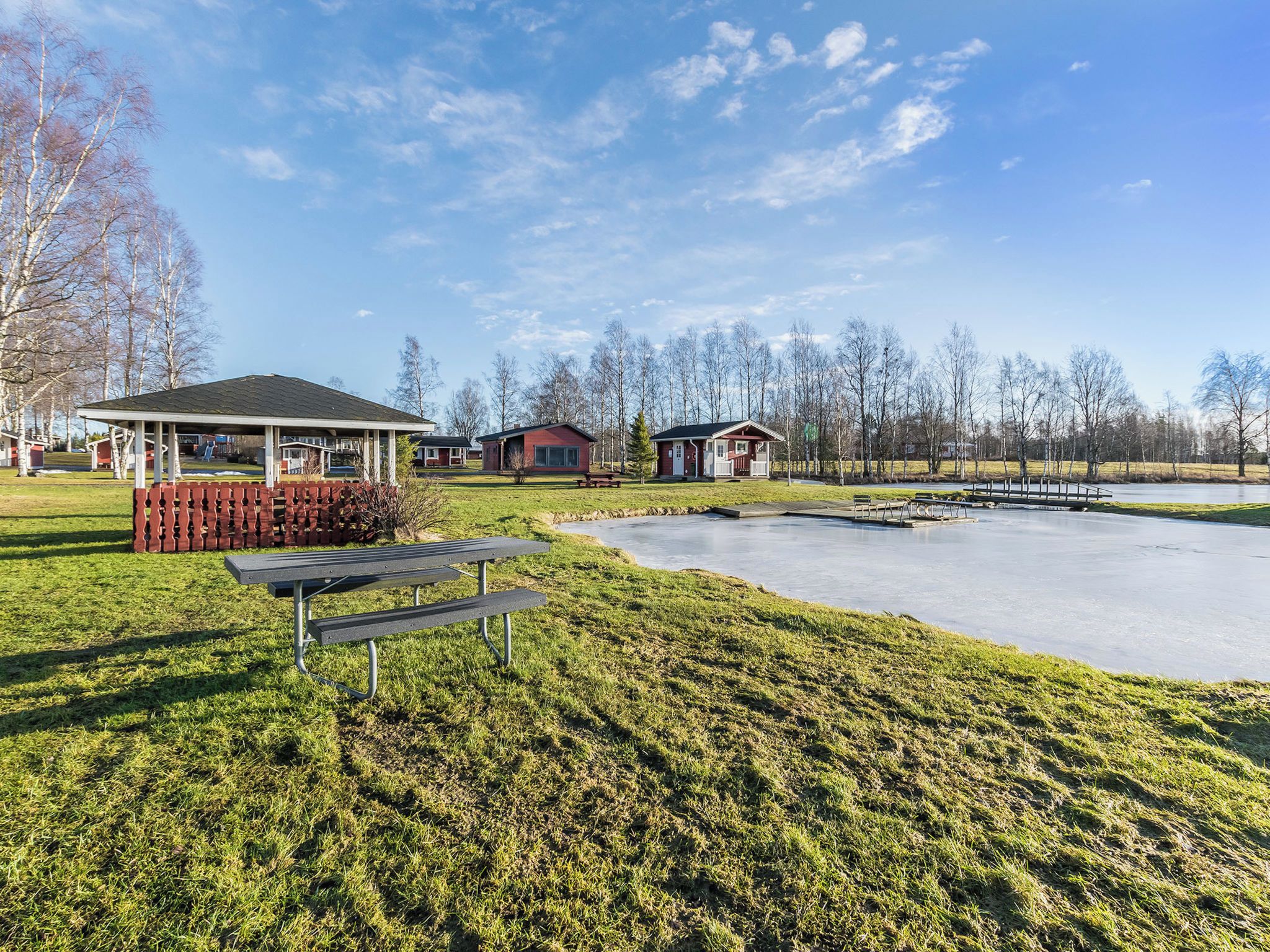 A park with picnic tables, a gazebo, and small cabins.