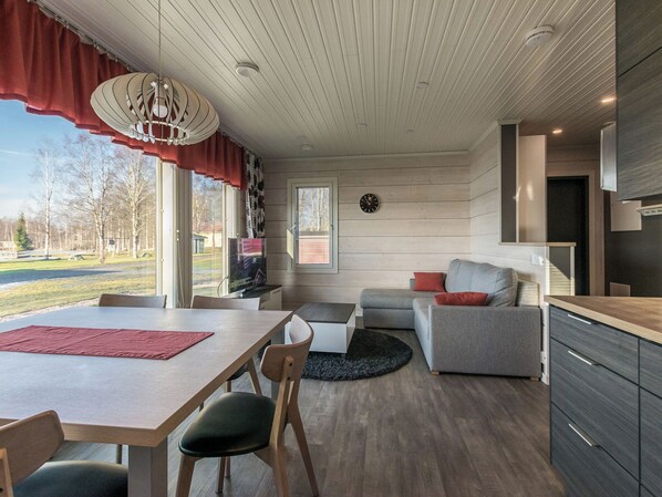 En moderne opholdsstue med spiseplads, sofa, fjernsyn og et køkken.