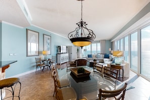 Relax in a spacious living area with a high ceiling and large windows offering a view of the outdoors.