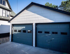 A two-car garage attached to a house with a gabled roof and white siding. - Downtown Historic Charmer - Walk to State Capitol (Carson City)