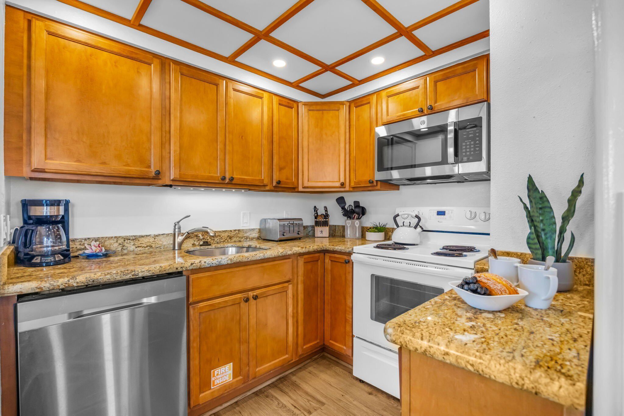 A kitchen with wooden cabinets, stainless steel appliances, granite countertops, and a dishwasher.