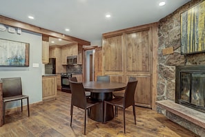 A modern kitchen with wooden cabinets, a dining table with chairs, and a stone fireplace. - The Lodge at Vail 2 BR Condo in the Heart of Vail by RedAwning - Save 20% on 7+ Nights! (Vail)