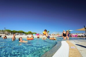 A swimming pool with people enjoying the water, a lifeguard tower, and a clear blue sky. - Water park for kids in Valras-Plage (Sérignan)