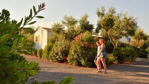 Two people walking on a paved path in a residential area with houses and lush greenery. - Mobile home in Bessan with terrace (Bessan)
