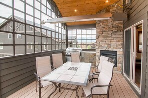 An outdoor patio with a table and chairs, a stone fireplace, and a view of the surrounding area.