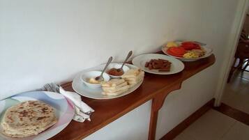 Una mesa de comedor con platos de comida, incluyendo pan plano, un bol de salsa y un plato de verduras.