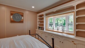 A bedroom with a bed, built-in shelving, a window with blinds, and a decorative wall piece. - Waterfront Annapolis Cottage: Fire Pit & Pier (Annapolis)