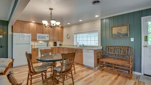 A kitchen with wooden cabinets, a dining table with chairs, a built-in bench, and a refrigerator. - Waterfront Annapolis Cottage: Fire Pit & Pier (Annapolis)