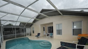 An indoor swimming pool with a glass ceiling, surrounded by lounge chairs and a small table. - Palmview Villa - your perfect retreat in Clermont by Paradise Resort Vacations! (Clermont)
