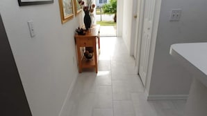 A hallway with white tiled flooring, a wooden table with decorative items, and a white counter on the right. - Palmview Villa - your perfect retreat in Clermont by Paradise Resort Vacations! (Clermont)