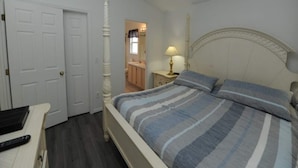 A bedroom with a bed, a nightstand, a lamp, a desk with a laptop and remote, and a door. - Palmview Villa - your perfect retreat in Clermont by Paradise Resort Vacations! (Clermont)