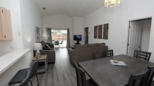 A modern living room with a dining area, a sofa set, and a television. - Palmview Villa - your perfect retreat in Clermont by Paradise Resort Vacations! (Clermont)
