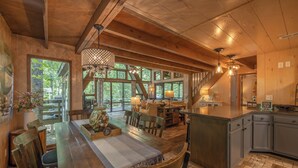 A spacious kitchen with wooden cabinets, a large island, and a dining area with a wooden table and chairs. - The Treetop Escape by Innsbrook Vacations! (Innsbrook)